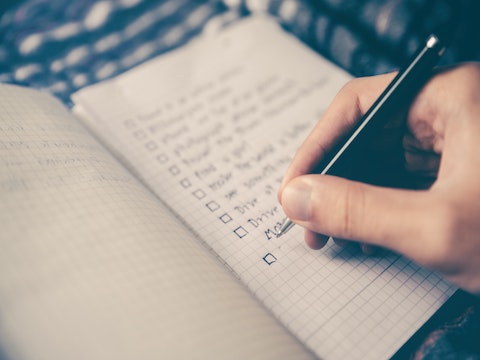 a person writing out a checklist in a notebook