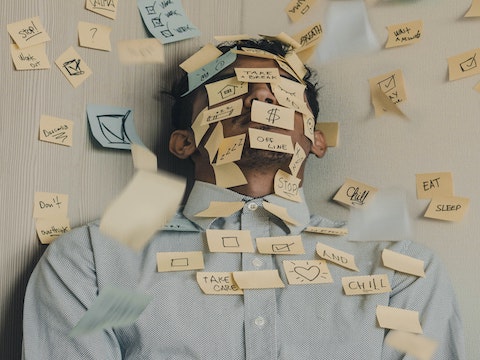 a man covered in sticky notes meant to display all the things he has to do.